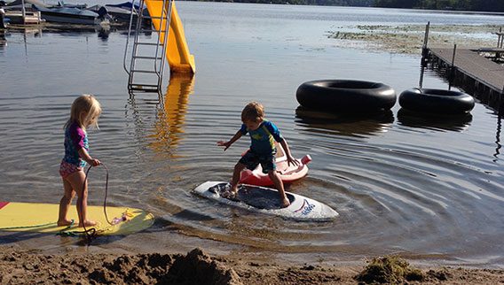 A child is riding on the water with a surfboard.